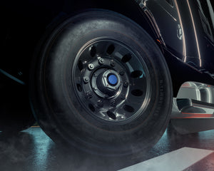 Close-up of a black tire with a detailed hub cap on a heavy-duty truck.